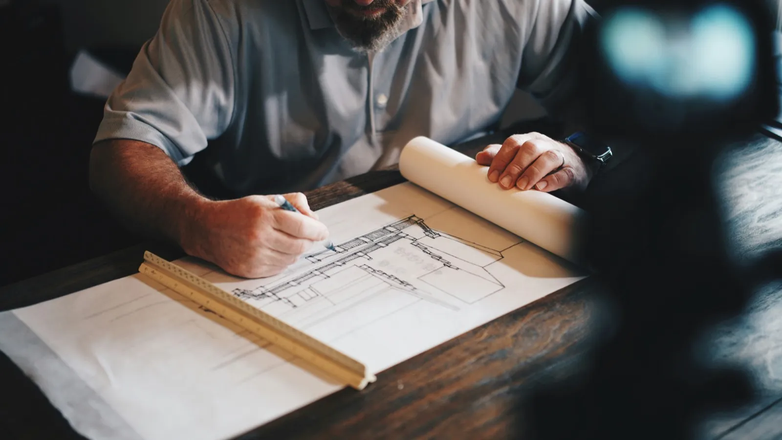 Contractor marking up a floor plan with a ruler and pencil