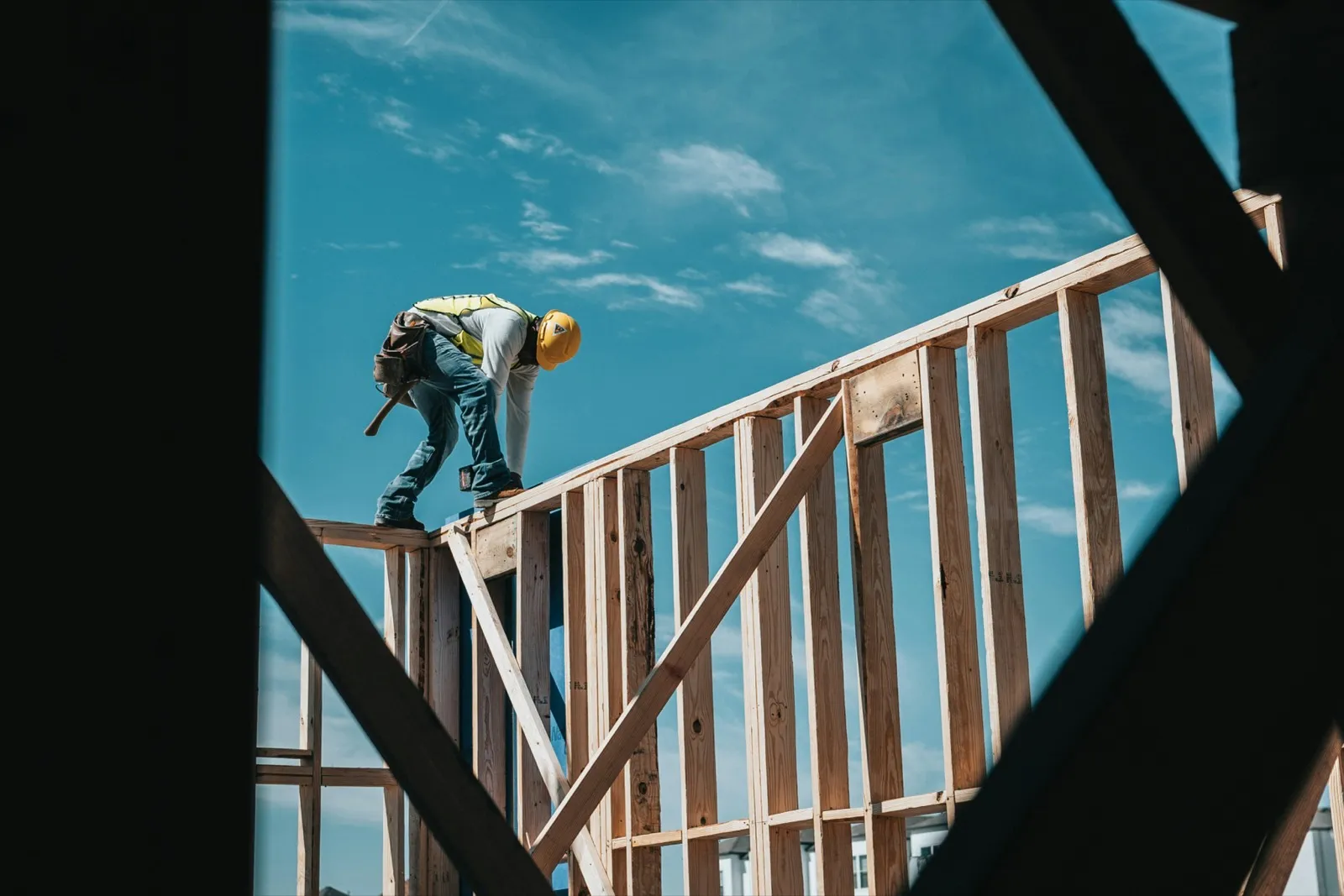 Framer working along a wall plate against an open blue sky