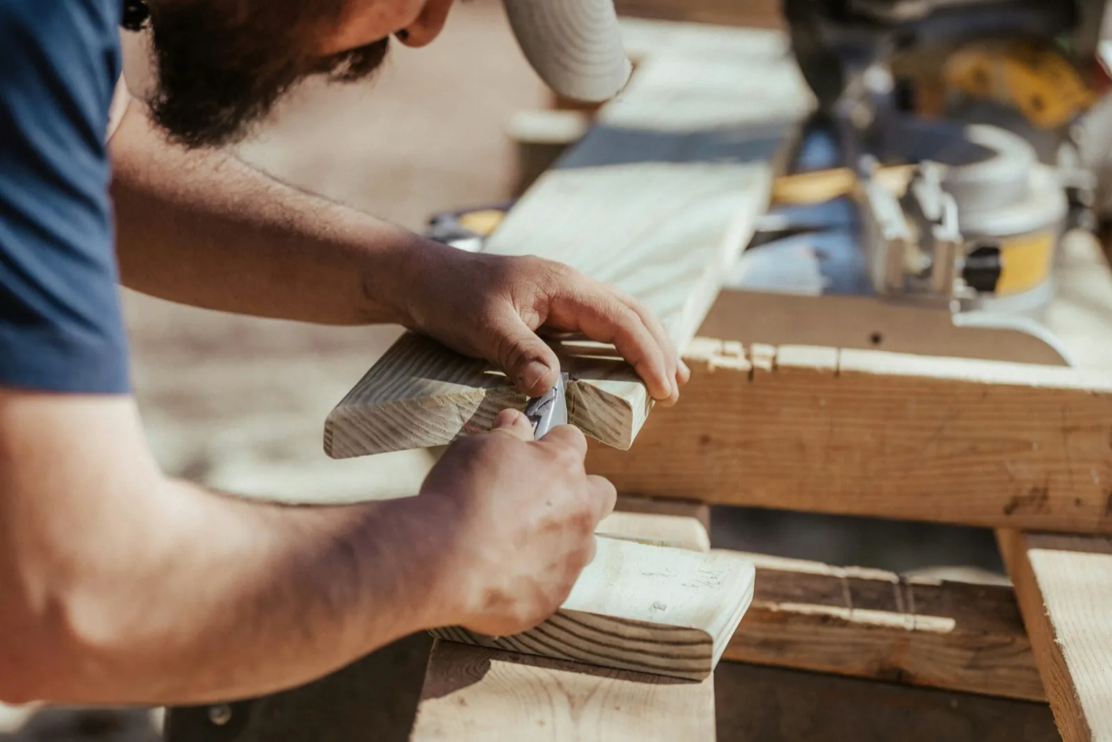 Carpenter shaping a length of trim by hand at a bench