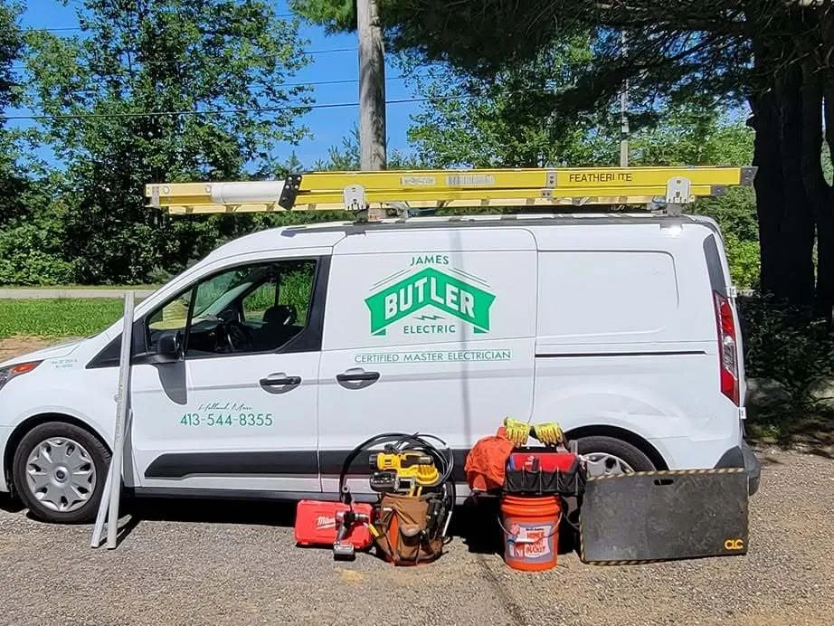 James Butler Electric's work van, lettered Certified Master Electrician, with a ladder on the roof and Jim's tools lined up beside it