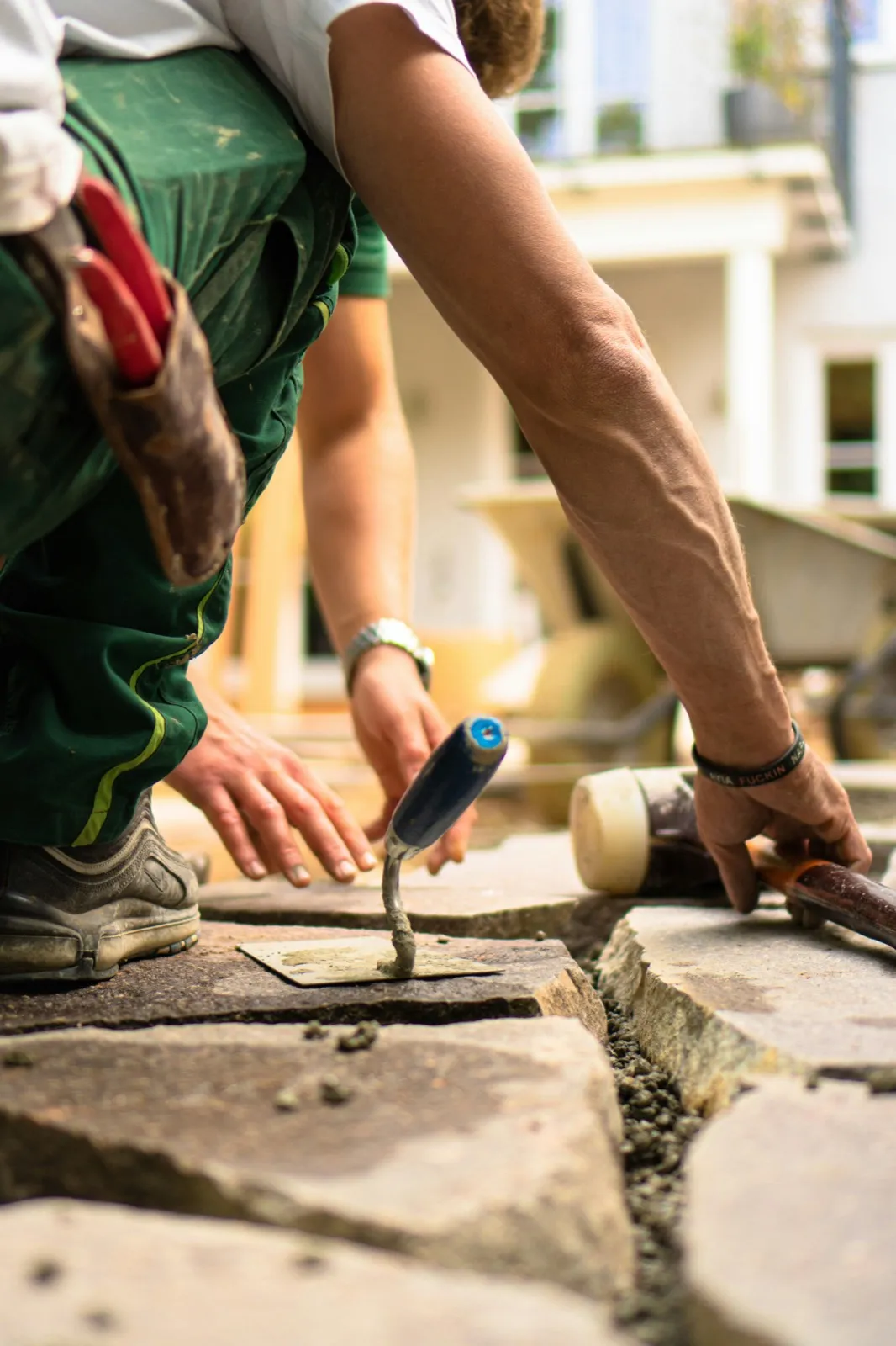 Landscaper setting a stone paver into place by hand