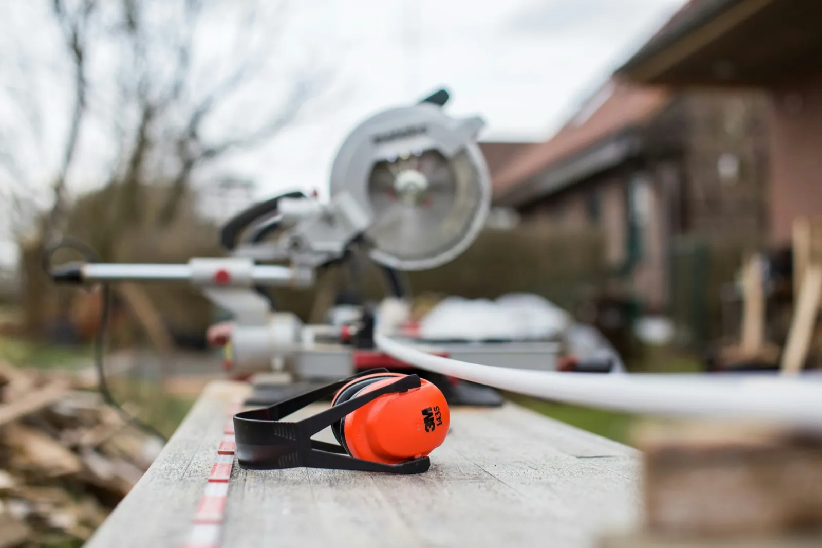 Miter saw and ear protection resting on a plank at the end of a work day